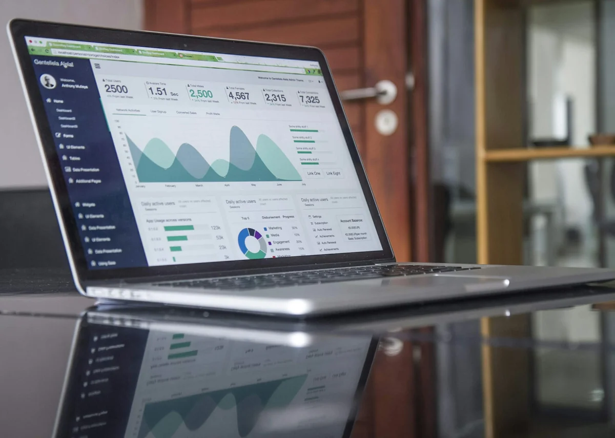 Laptop showing a sales dashboard with an area chart and metric tiles