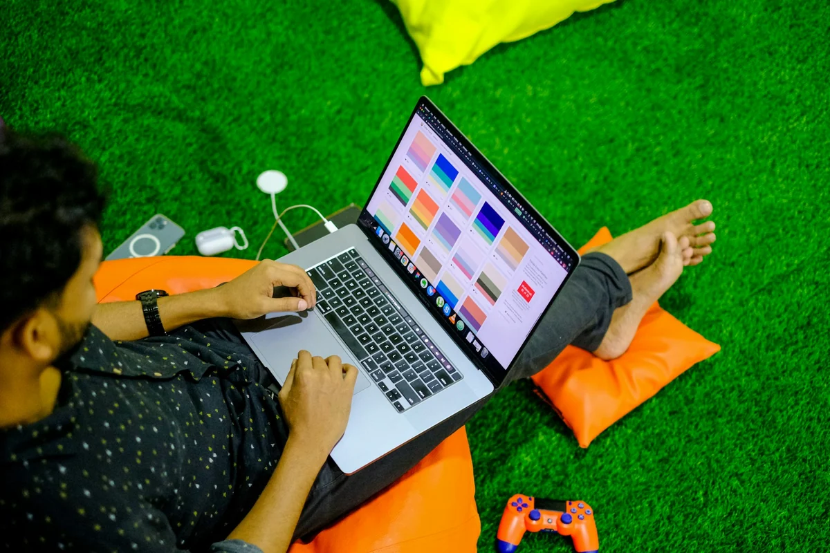 Người ngồi trên thảm cỏ nhân tạo chỉnh thiết kế nhiều màu trên laptop