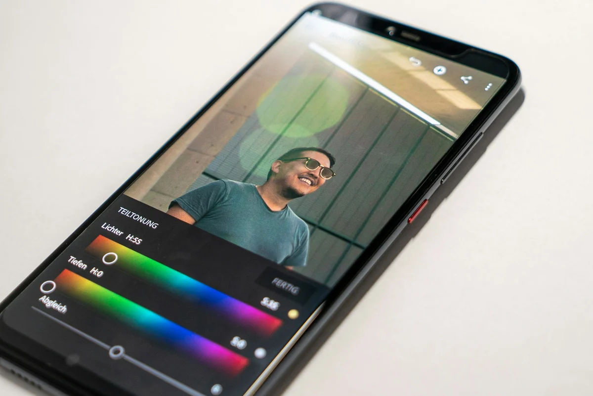 An Android phone showing a photo color editing tool on a white table