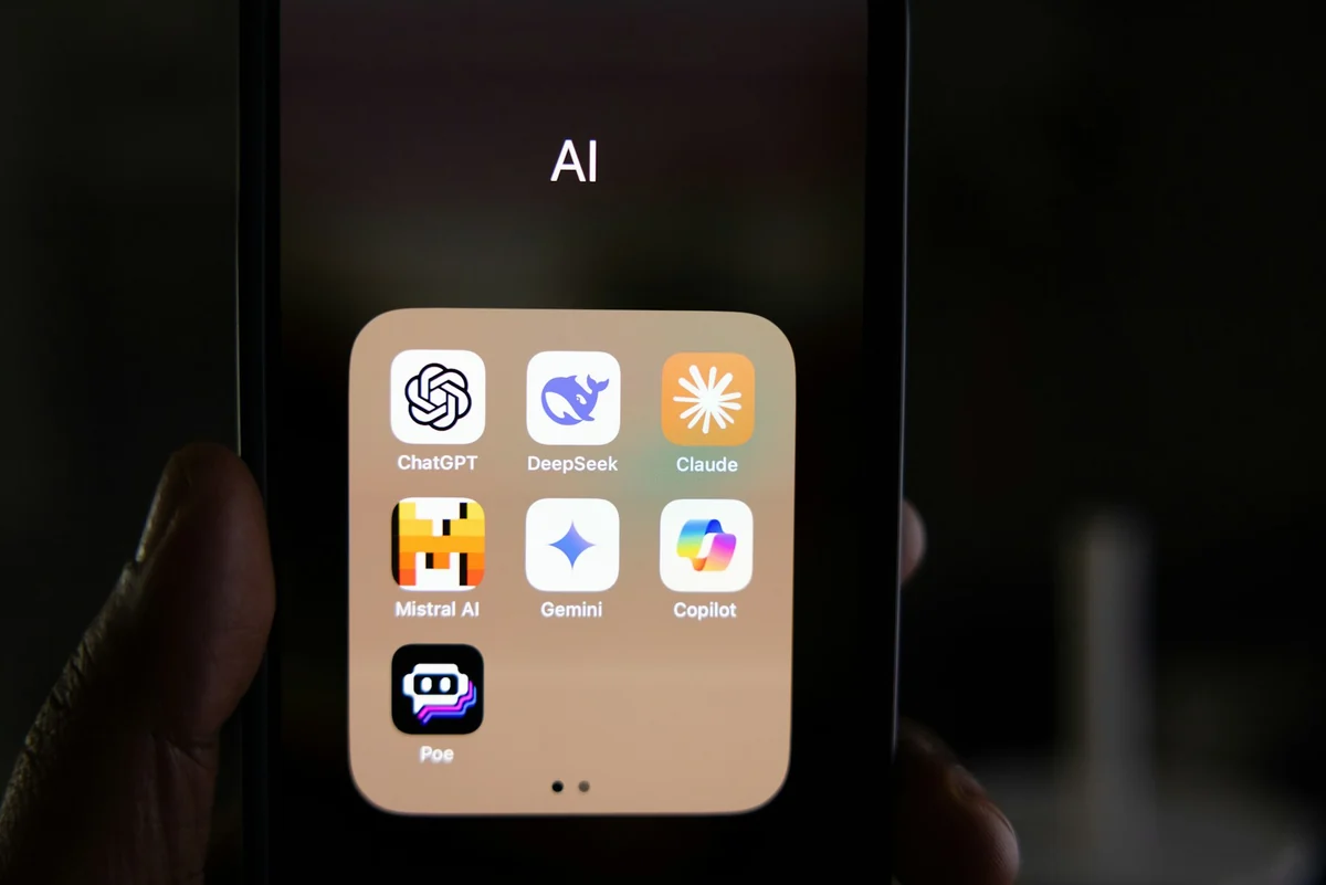 A phone screen with an AI folder holding the ChatGPT, DeepSeek, Claude, Mistral AI, Gemini, Copilot and Poe apps