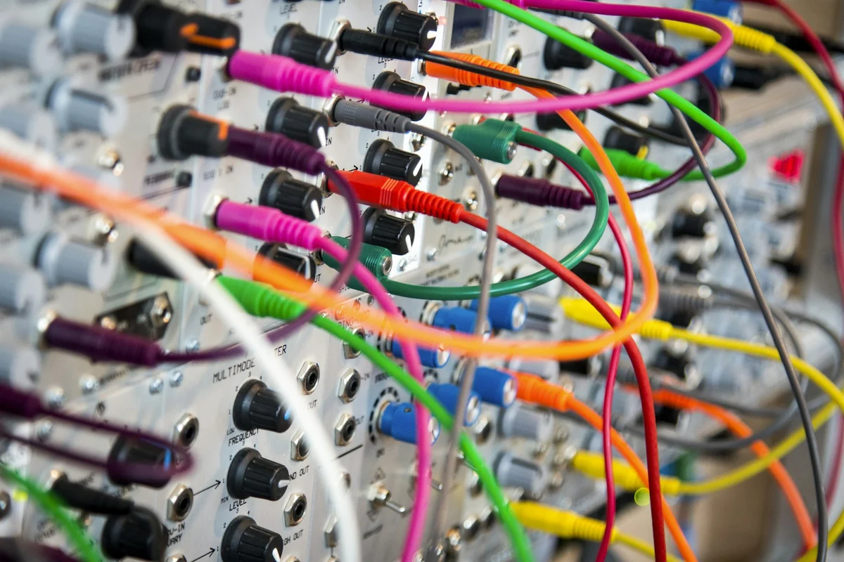 Many colorful cables plugged into identical ports on an equipment panel