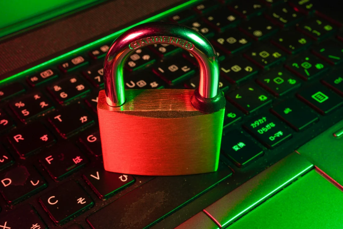 A red padlock resting on a laptop keyboard that glows green