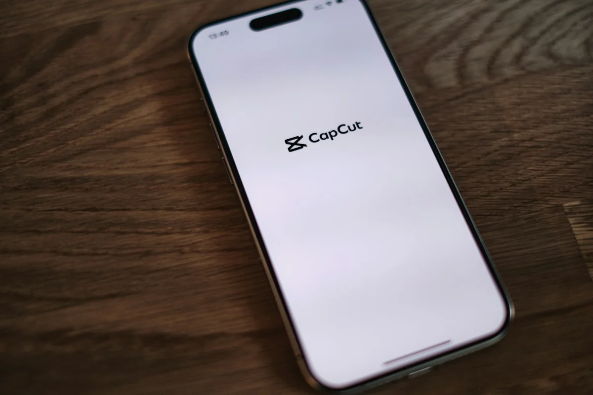 A phone on a wooden table showing the CapCut app launch screen