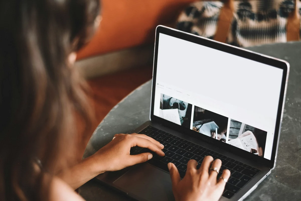 A person scrolls through a set of photos on a laptop screen on a desk