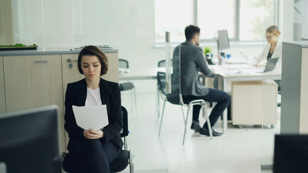 A job candidate reading a sheet of paper in a bright office while waiting for an interview
