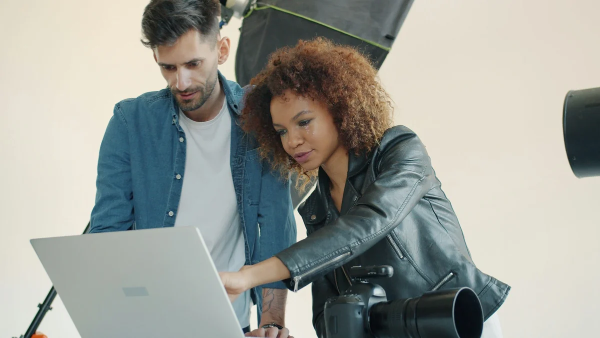 Two people in a studio looking at and choosing reference photos on a laptop