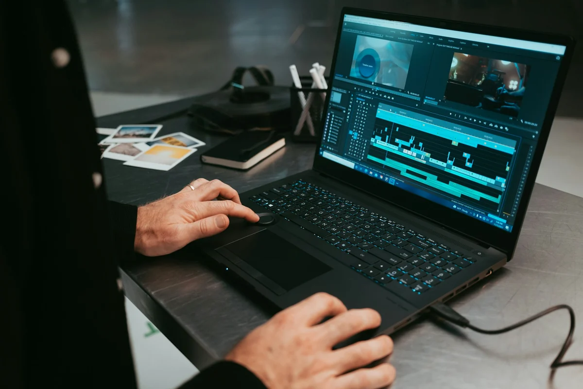 A person editing video on a laptop with a timeline of several clips joined together