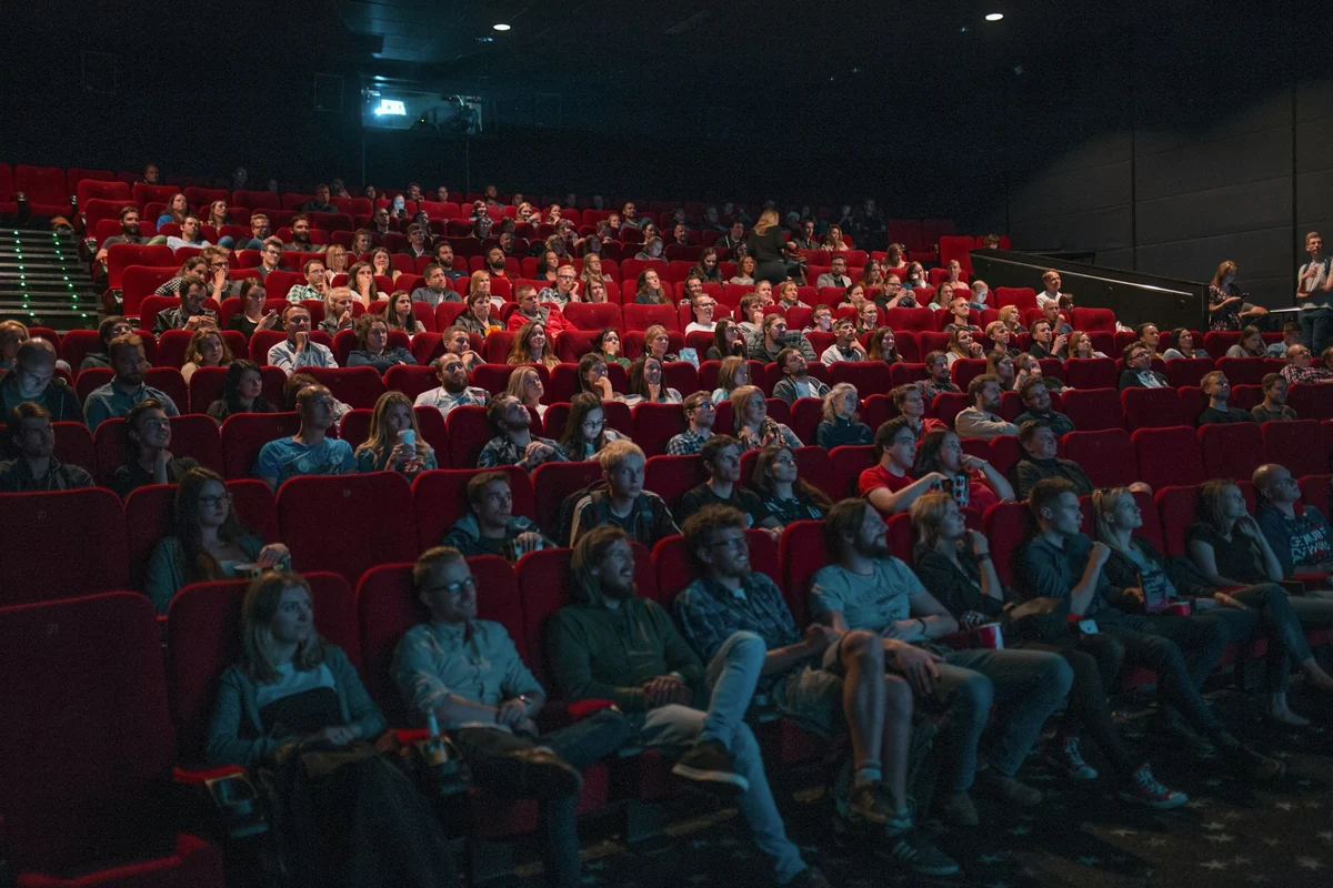 An audience filling rows of red seats in a movie theater, watching the screen